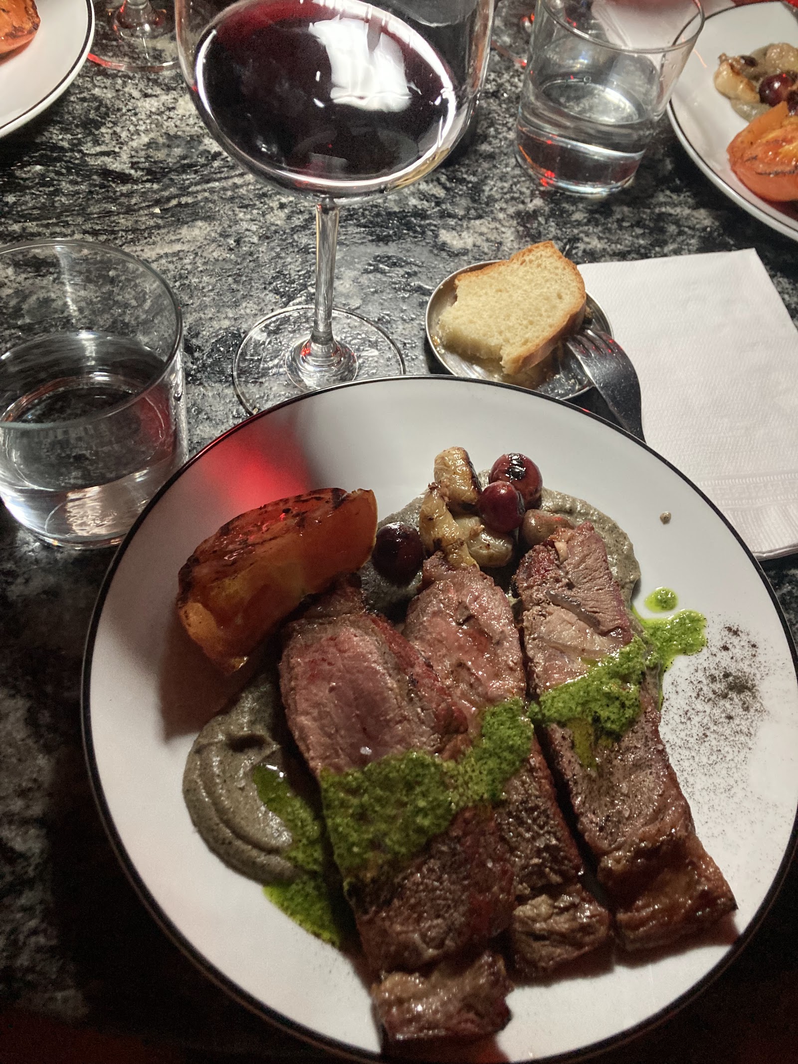 Plato de carne con puré ahumado y chimichurri maridado con vino tinto en HUGO